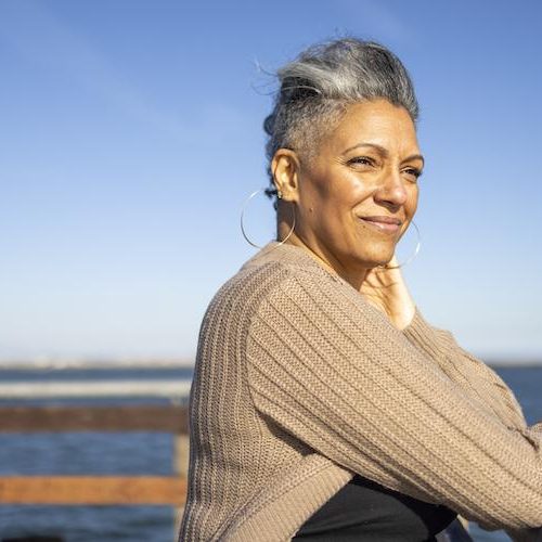 A mature black woman relaxes on the pier at the beach.